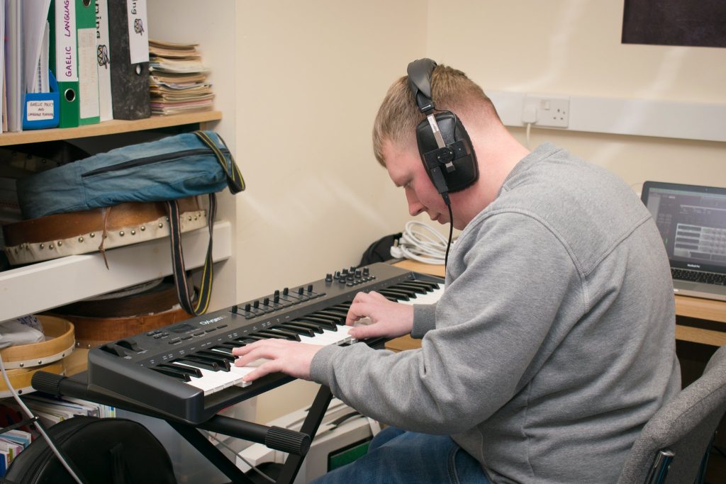Young Person playing keyboards and wearing headphones